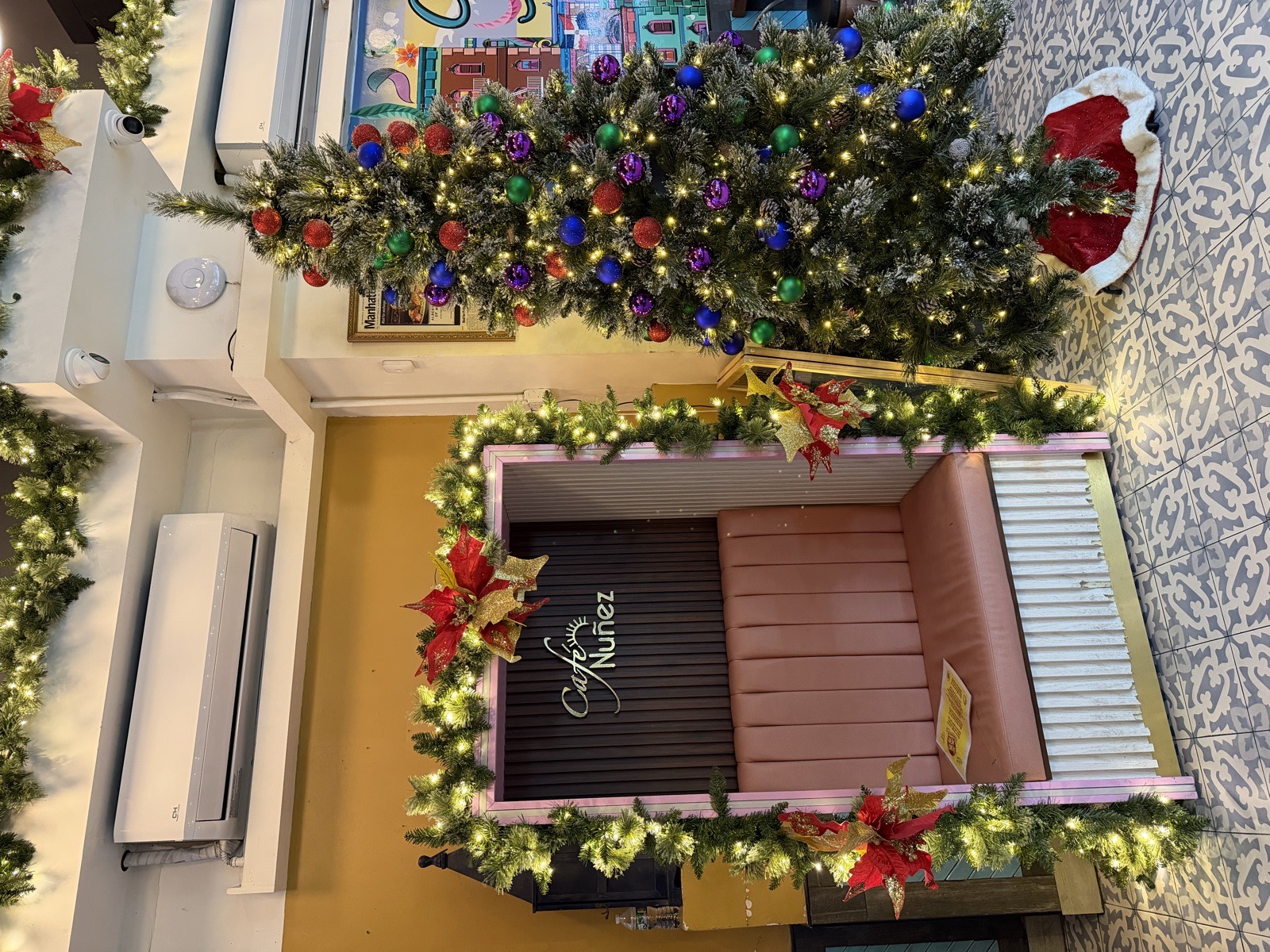 Fully decorated Christmas tree beside a garland-wrapped entry inside Café Nuñez