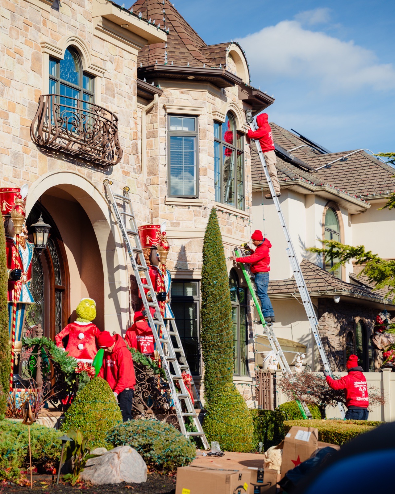 Two crew members in red company hoodies on ladders at a front entrance
