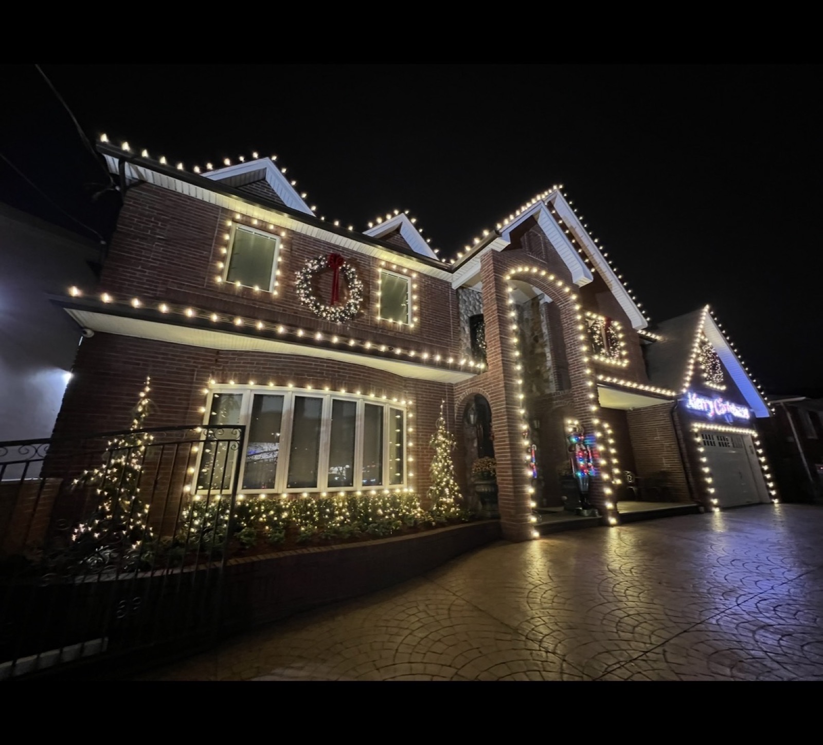 Brick home with lit gables, windows and a wreath