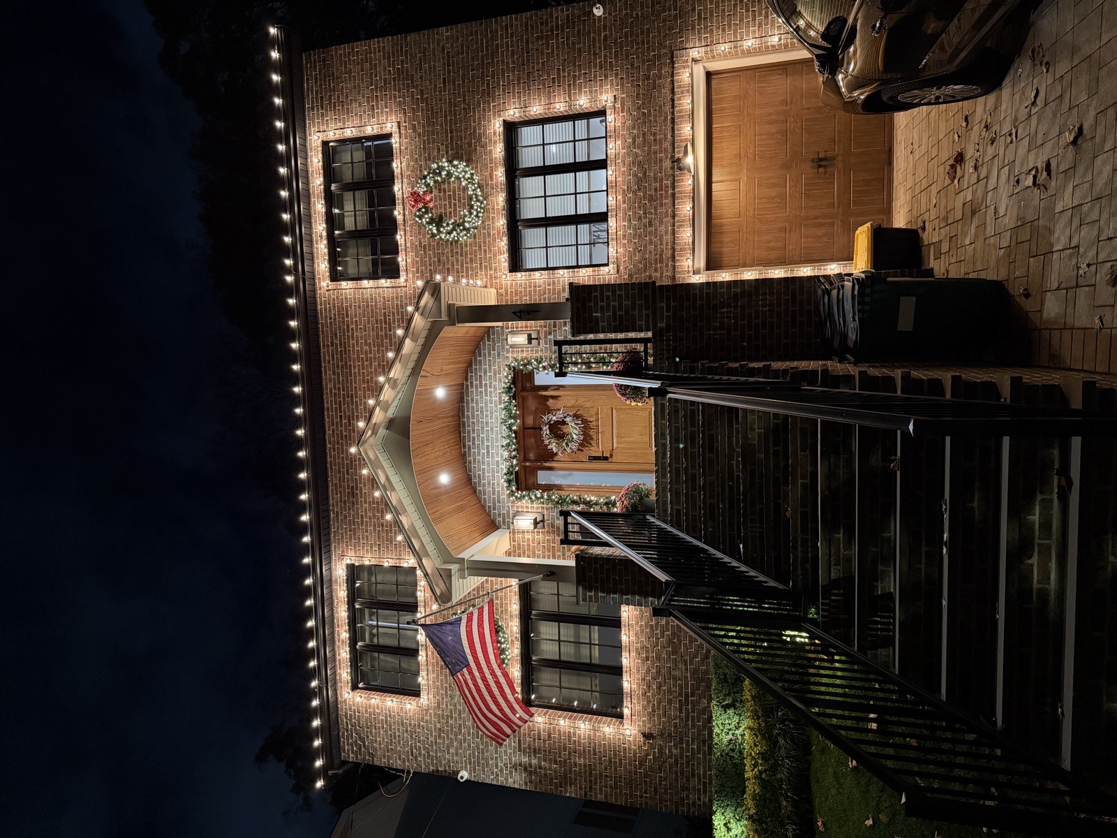 Brick home with lit stairs and an American flag