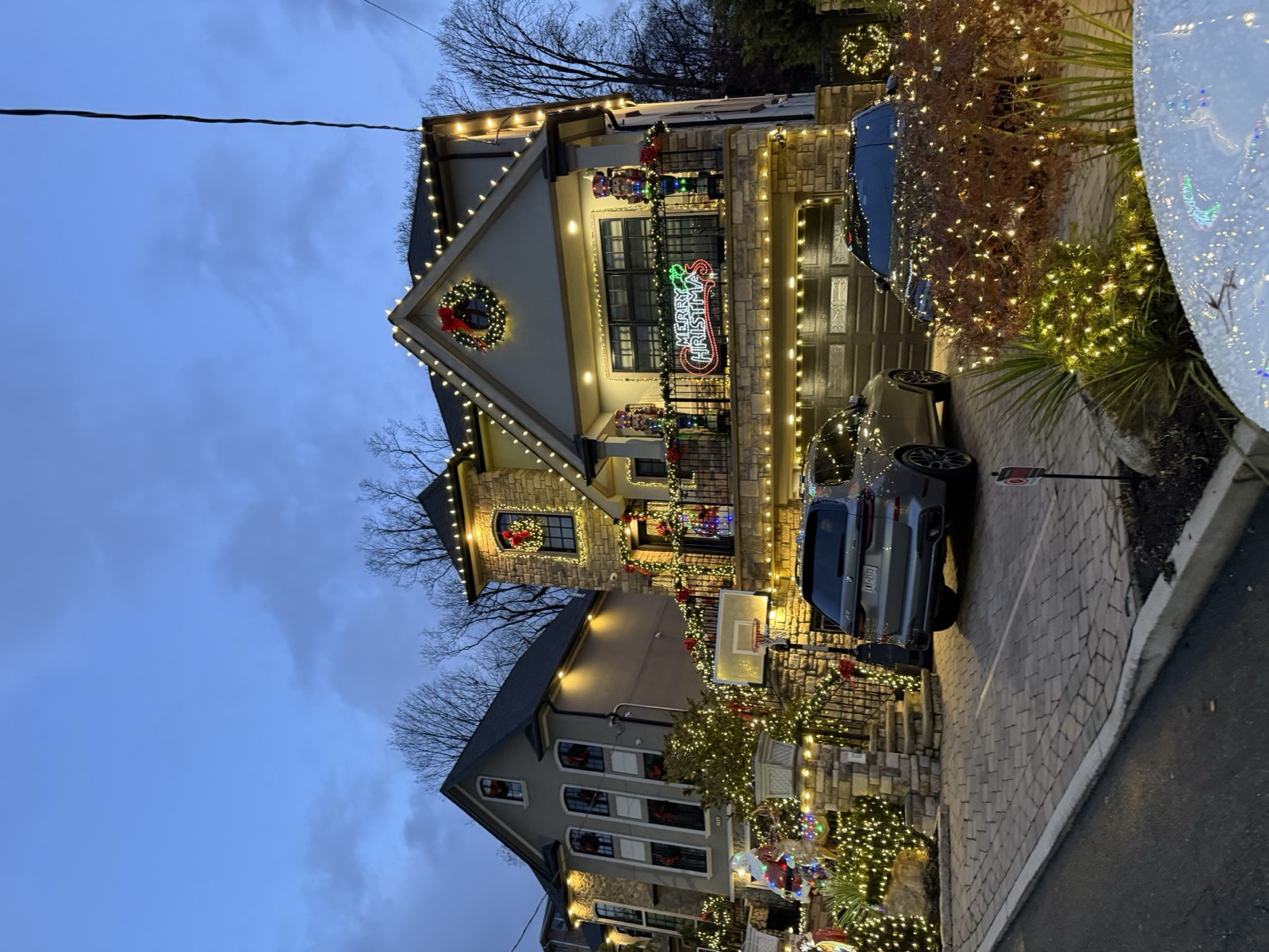 Three-story home outlined in lights at dusk