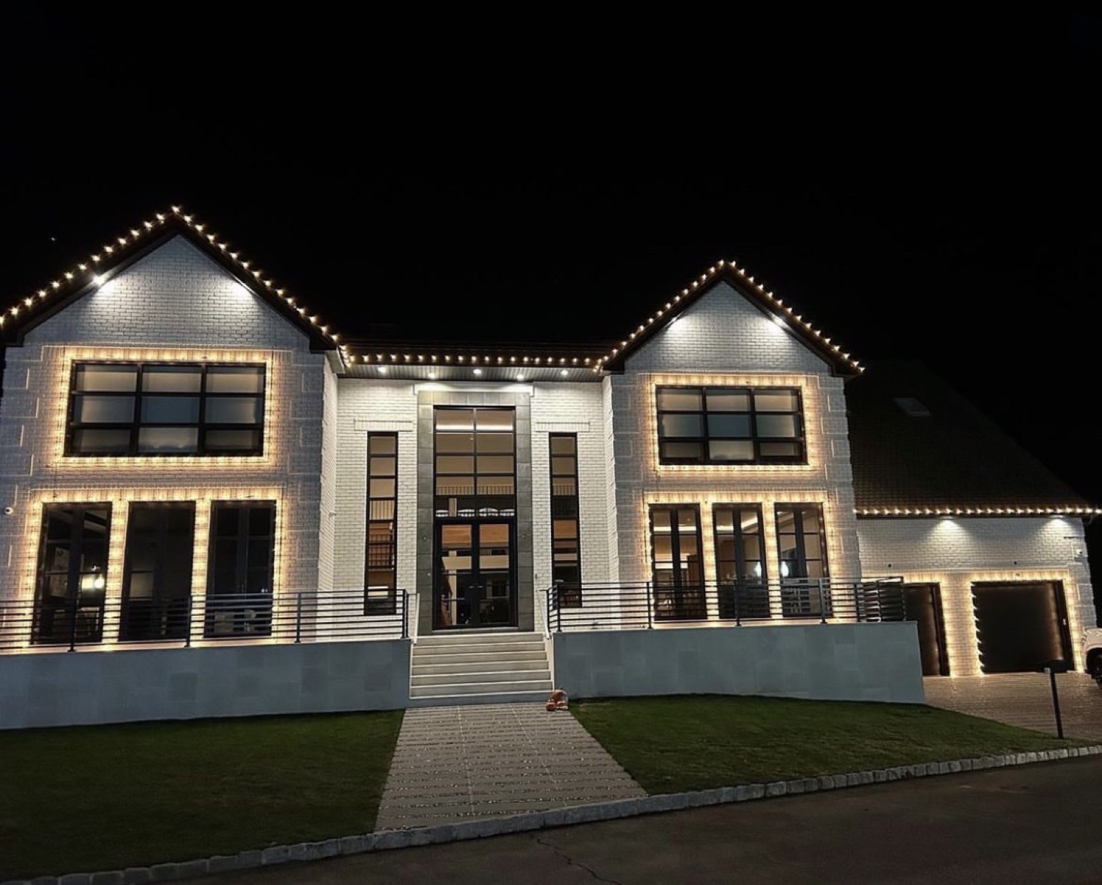Modern white home with every window outlined in warm-white lights